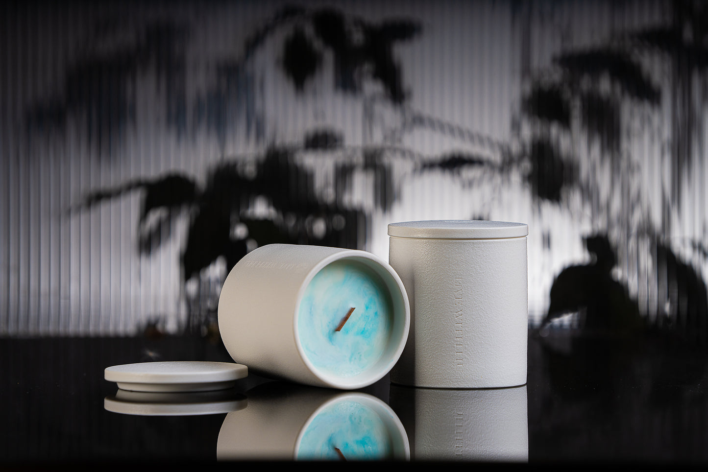 Grace candle is placed on a black reflective surface, with blurred plant shadows in the background. This portrait showcases the timeless ceramic vessel, as well as the luxury wax blend that is aesthetically colored.