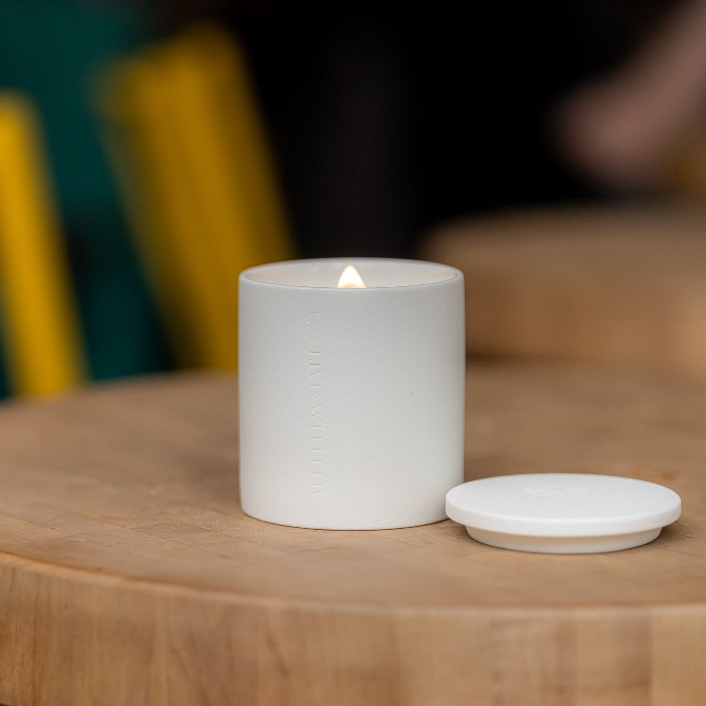 An elegant luxury candle on a wooden coffee table, the flame is in a triangle shape and steady, bringing a sense of calm and beauty.