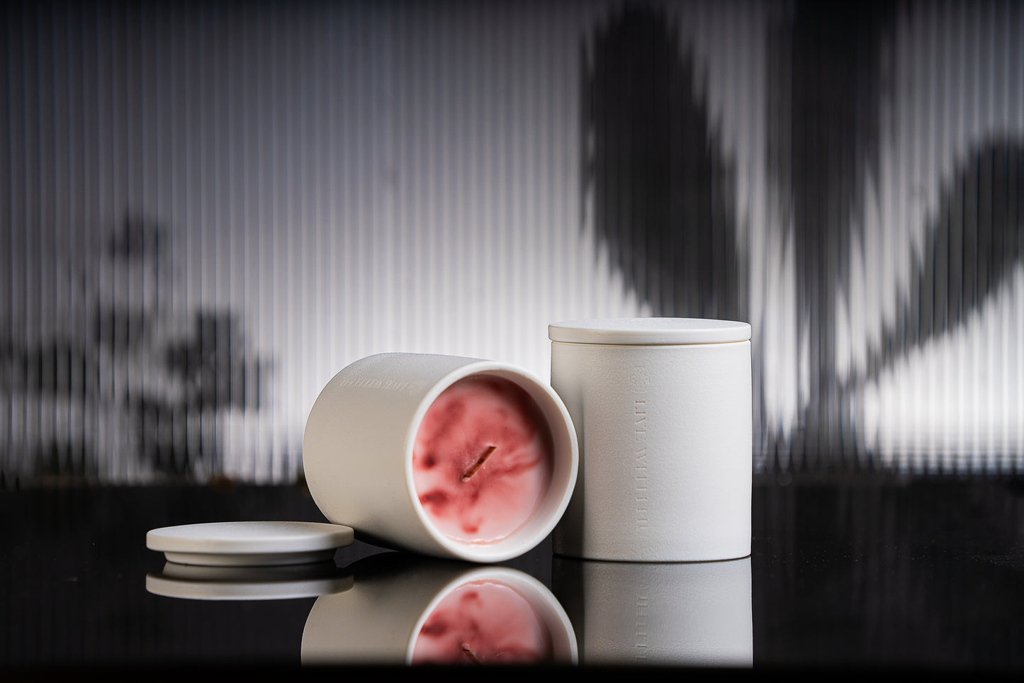 Blaze candle is placed on a black reflective surface, with blurred plant shadows in the background. This portrait showcases the timeless ceramic vessel, as well as the luxury wax blend that is aesthetically colored. 
