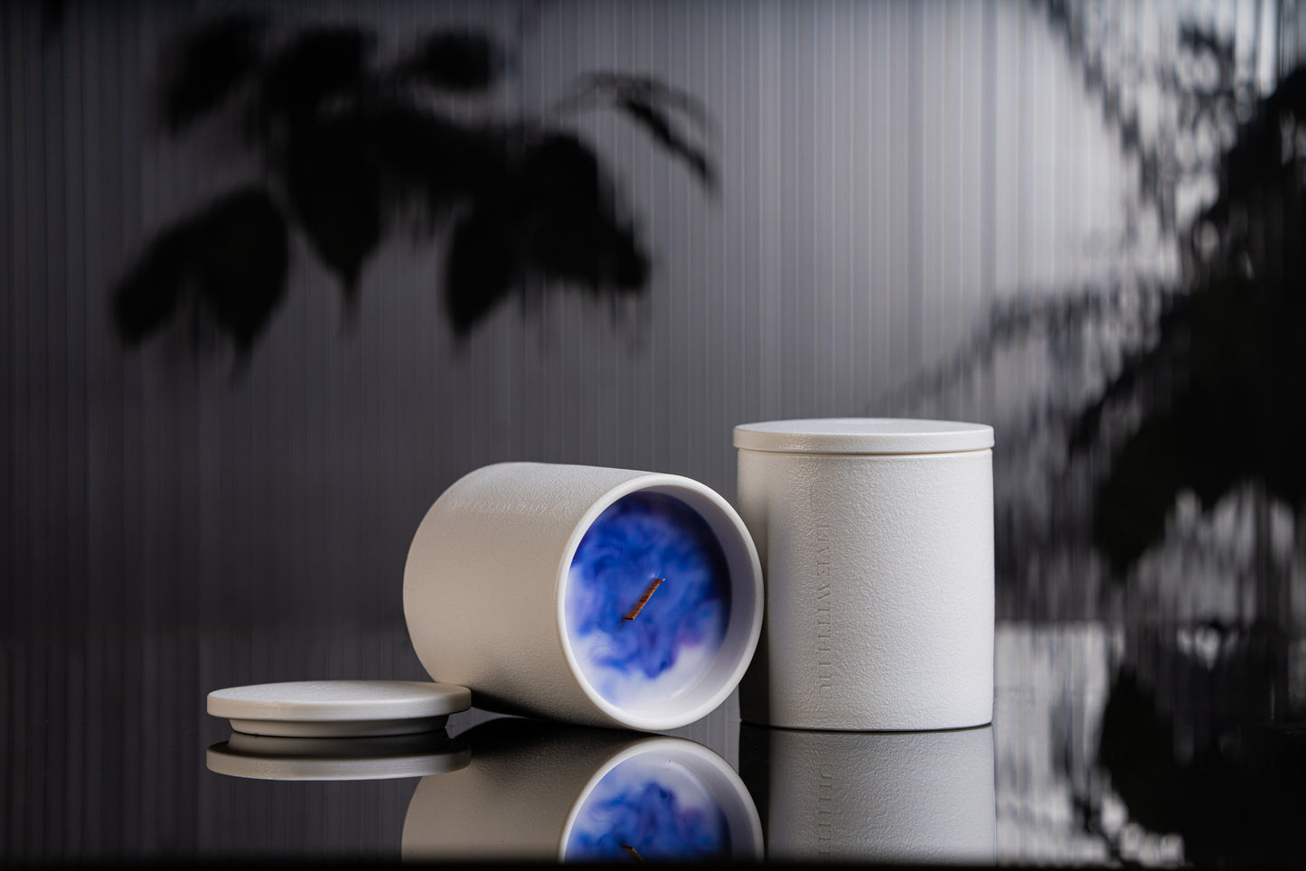 Radiance candle is placed on a black reflective surface, with blurred plant shadows in the background. This portrait showcases the timeless ceramic vessel, as well as the luxury wax blend that is aesthetically colored. 